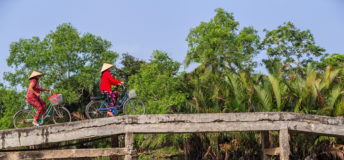 Vietnamese women riding bicycle, Mekong River Delta, Vietnam