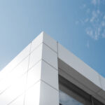 Building with white aluminum facade and aluminum panels against blue sky