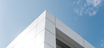 Building with white aluminum facade and aluminum panels against blue sky